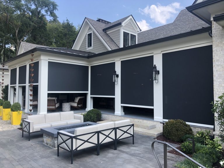 Seven Eclipse Power Screens with white frames and black fabric enclosing a covered patio