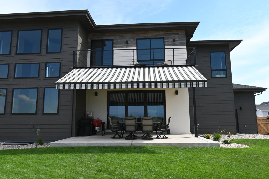 Striped Eclipse Premier retractable awning with drop shade over a back patio